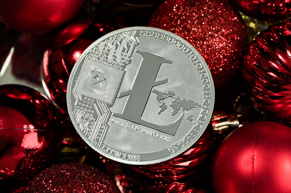 Una moneda de plata sentada encima de una pila de adornos rojos