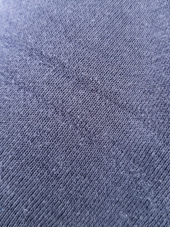 a close-up of a finely textured charcoal grey fabric, symbolizing refined craftsmanship.