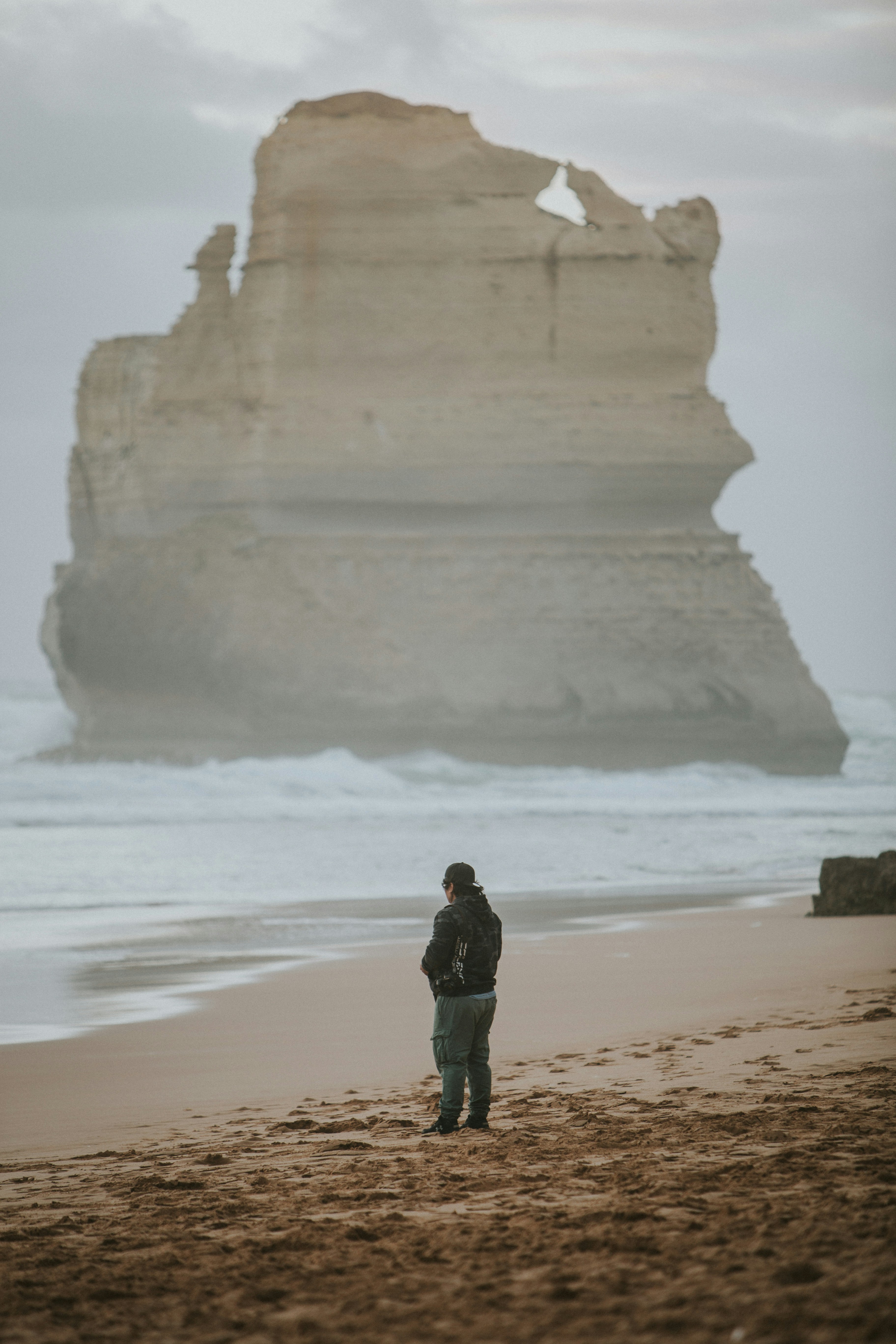a man standing on top of a sandy beach next to the ocean