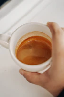 A steaming espresso shot pouring into a classic white ceramic cup with crema visible on top.