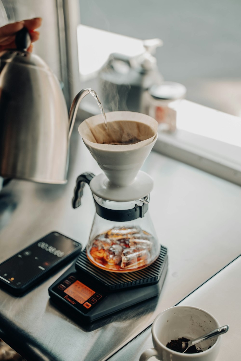 una cafetera sentada encima de una mesa junto a una taza de café