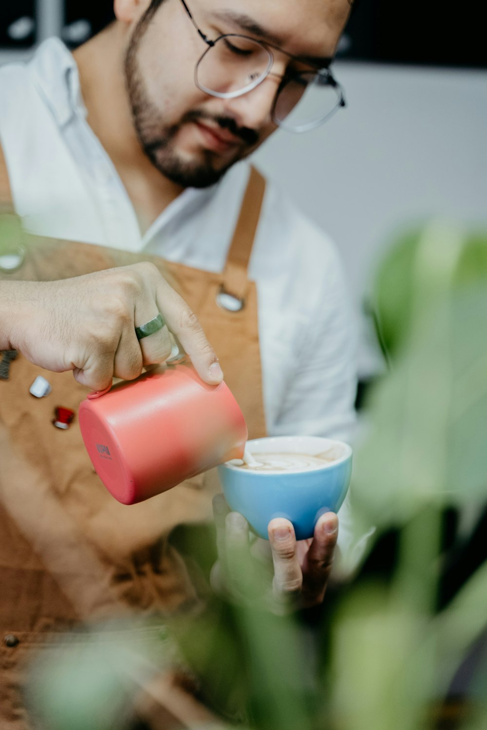 Un hombre vertiendo una taza de café en una taza azul