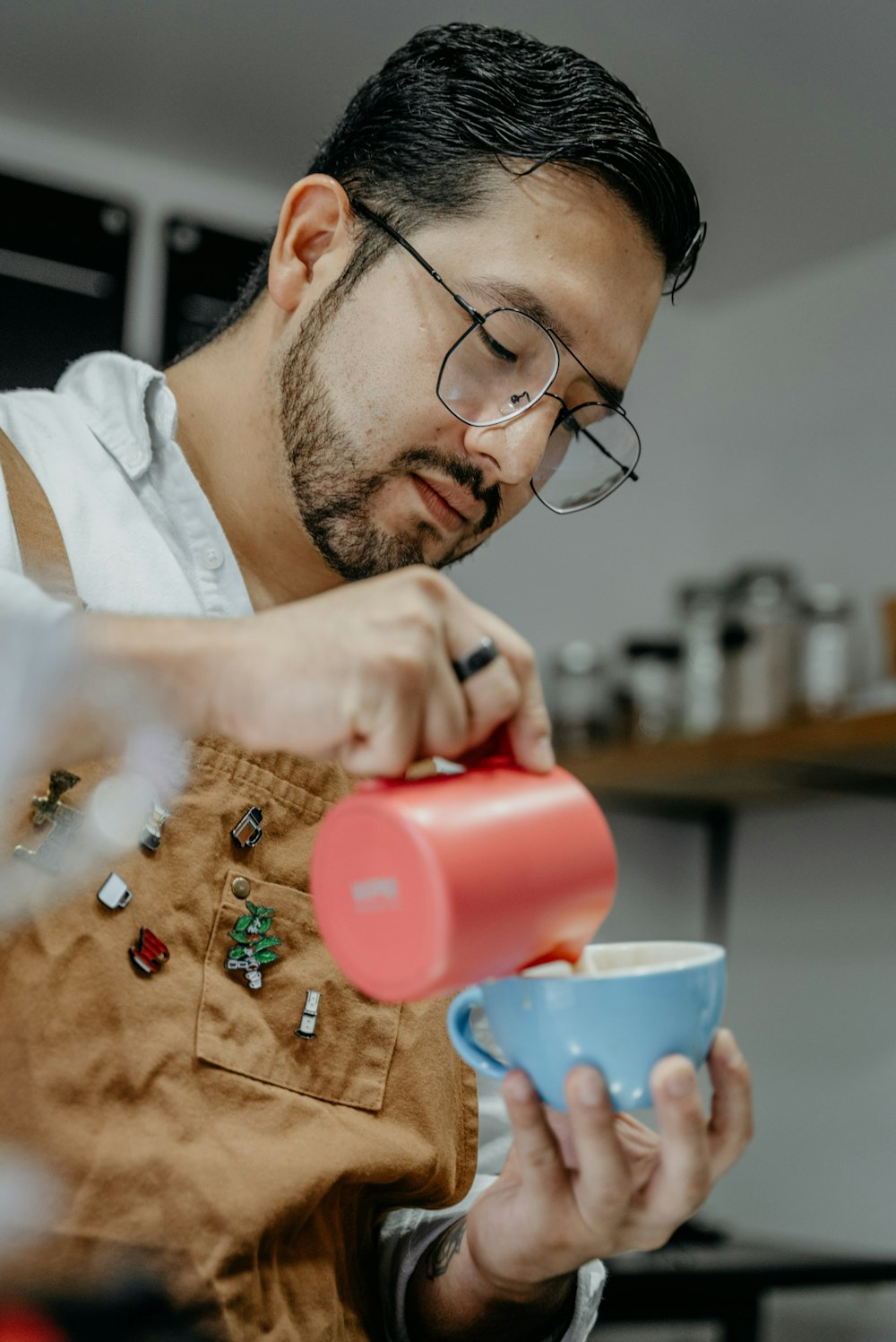 Un hombre vertiendo una taza de café en una taza azul