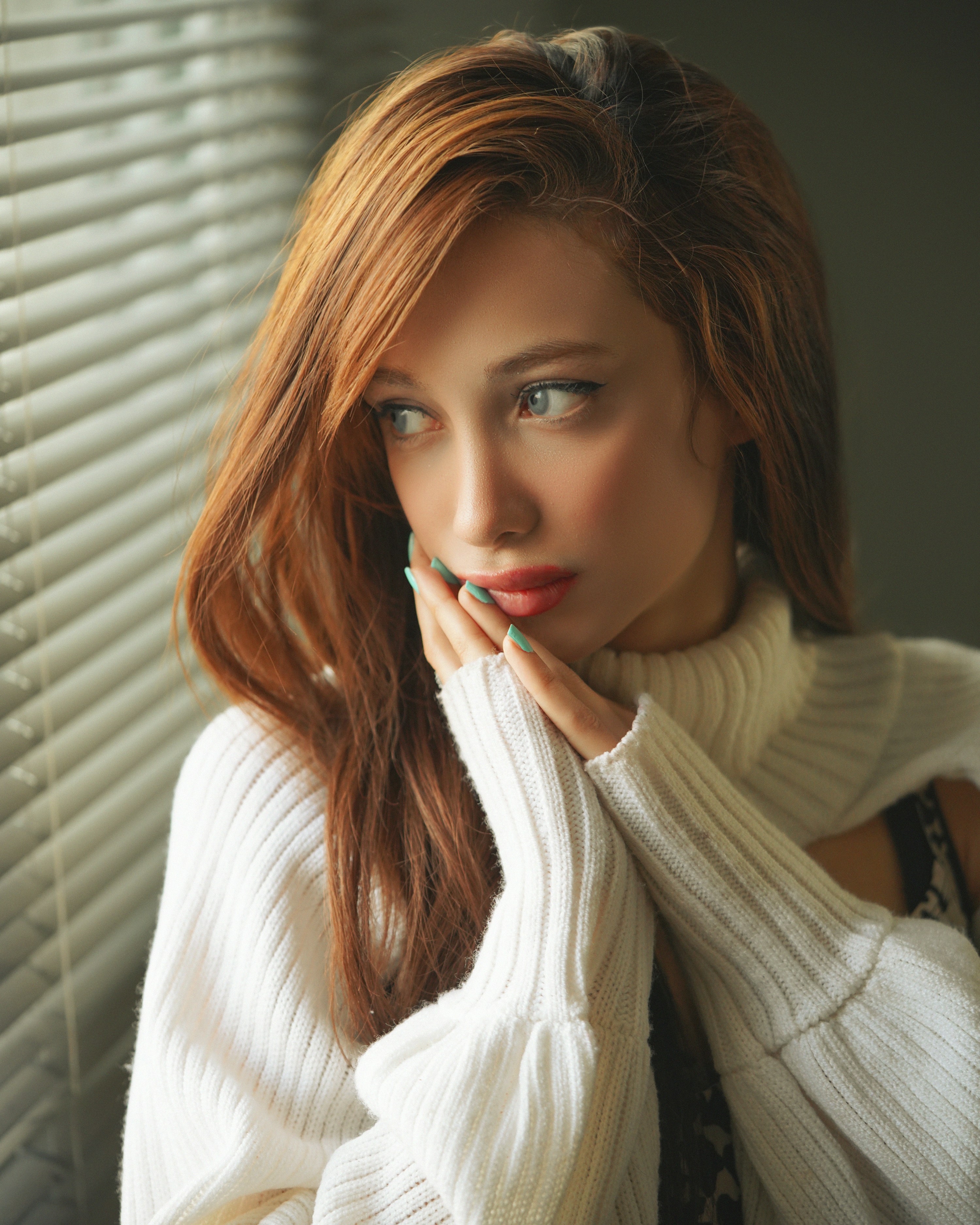 a woman with red hair wearing a white sweater