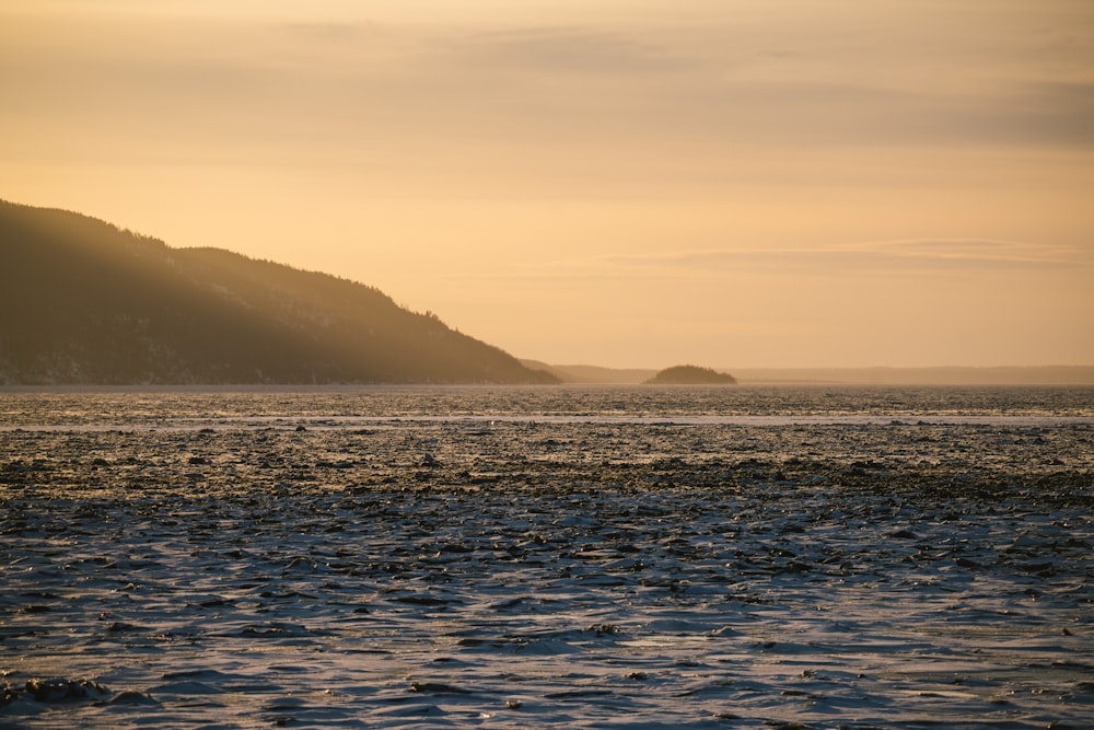 a large body of water with a mountain in the background