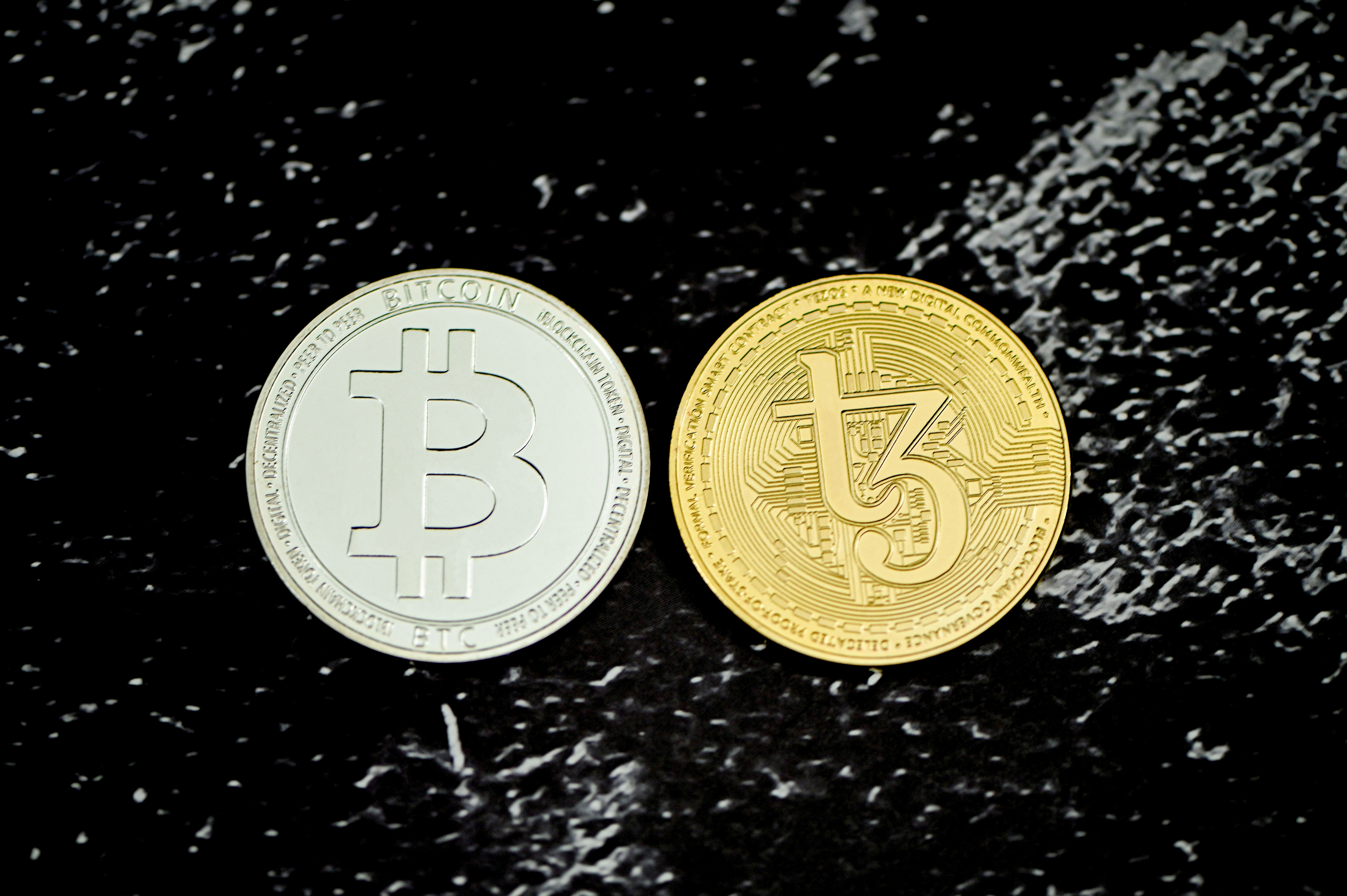 Bitcoin and Tezos coin are together on a marble background