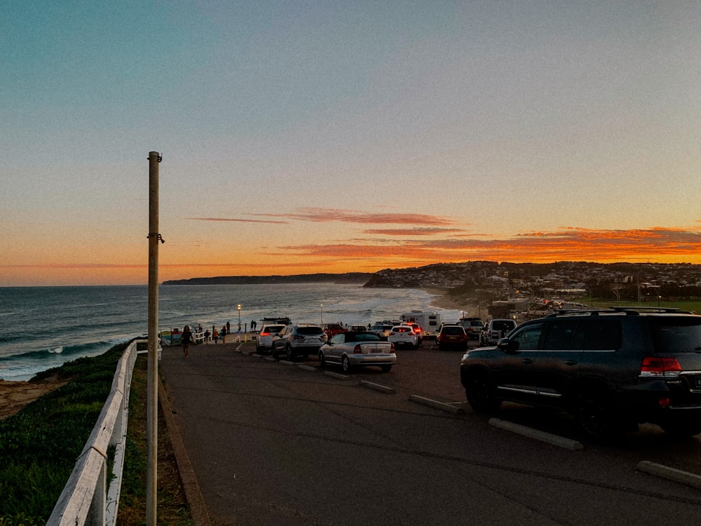 um grupo de carros estacionados ao lado de uma estrada ao lado do oceano