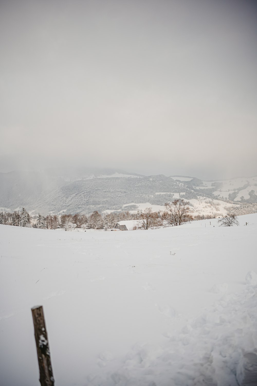 a snowy landscape with a fence in the foreground