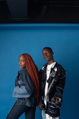 A stylish young man and woman wearing modern streetwear outfits posing confidently against a minimalist black and white backdrop.