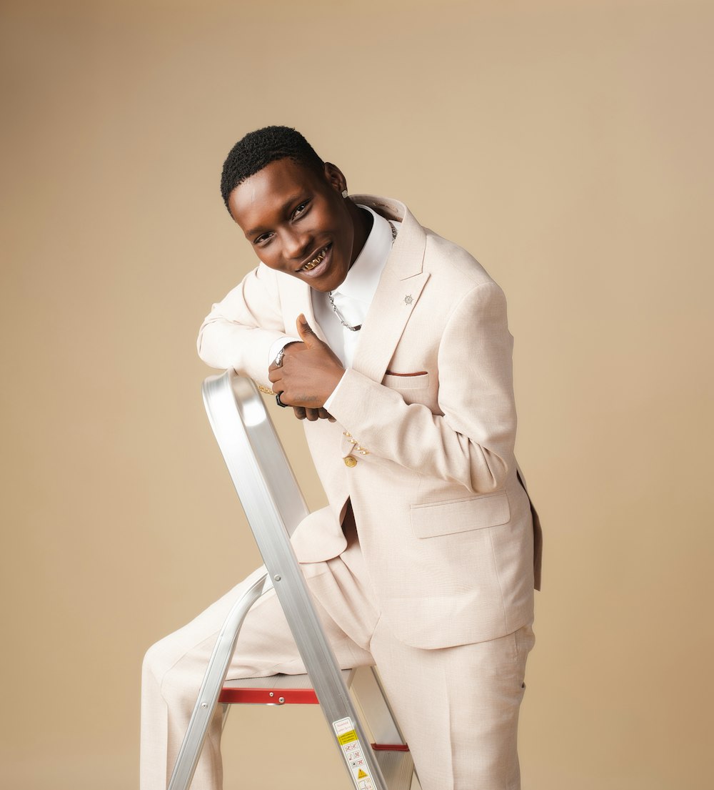 a man in a white suit leaning on a ladder