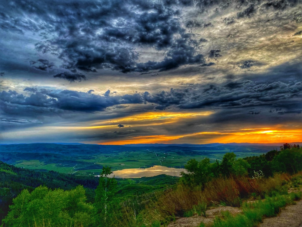 a scenic view of a lake and mountains under a cloudy sky