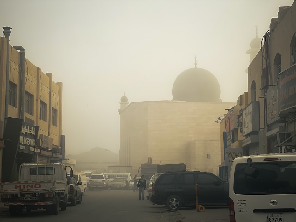 a foggy city street with cars parked on the side of the road