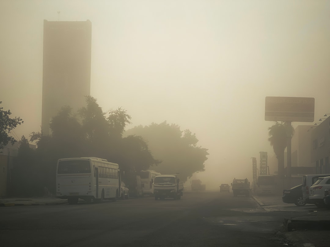 a foggy street with several buses parked on the side of the road,