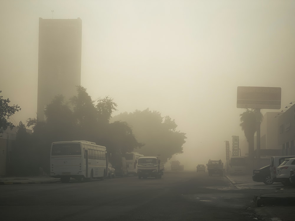 a foggy street with several buses parked on the side of the road