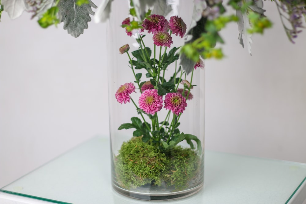 a vase filled with flowers and moss on a table