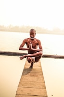 a man sitting on a dock doing yoga