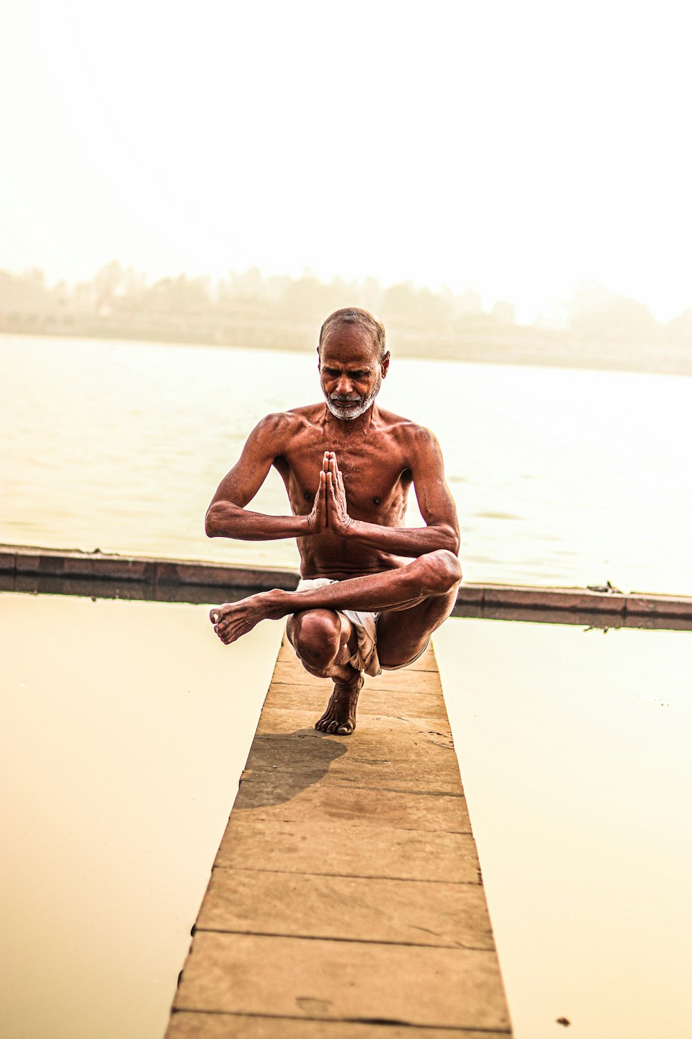 a man sitting on a dock doing yoga