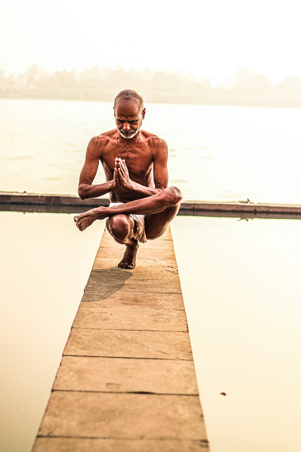a man sitting on a dock doing yoga