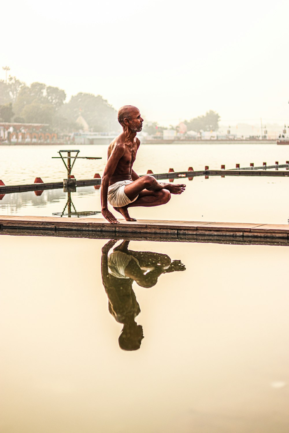 a man doing a yoga pose in front of a body of water