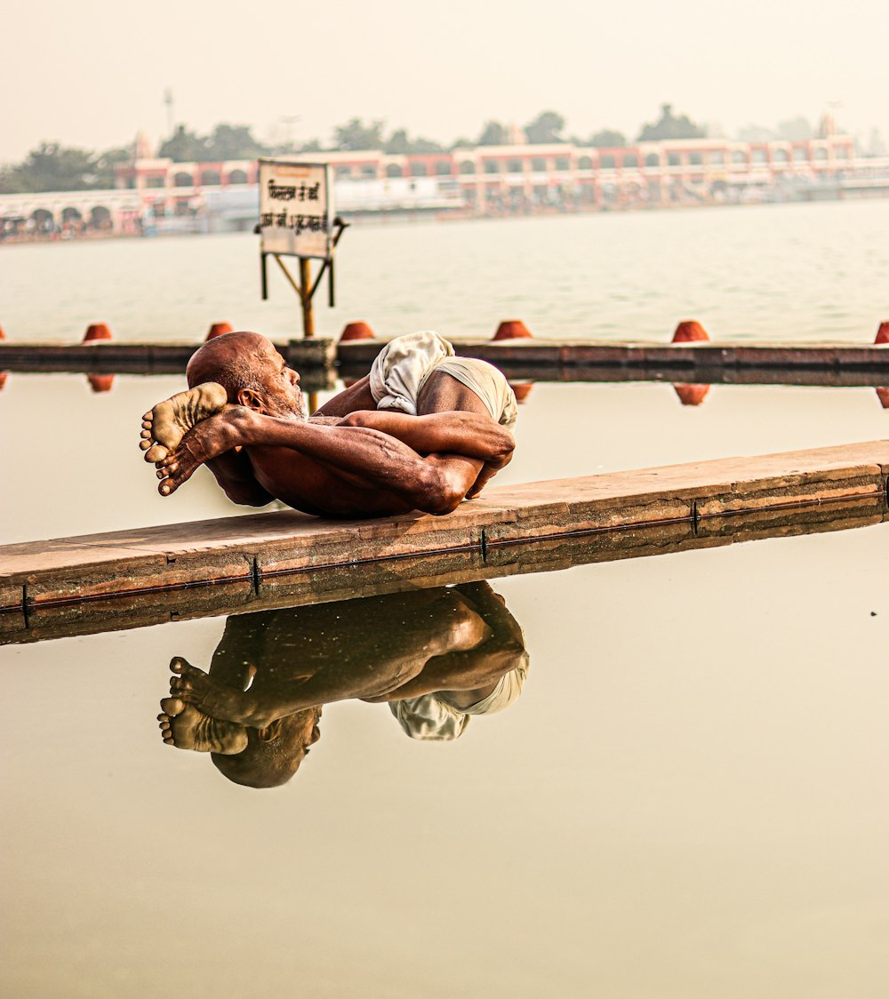 a man sleeping on a dock next to a body of water