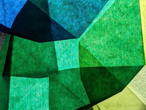 Geometric digital art with overlapping translucent shapes in blues and greens.