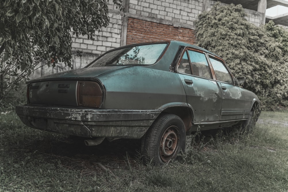 an old car sitting in the grass next to a building