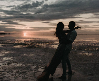 A passionate couple embracing under a sunset on a beach.