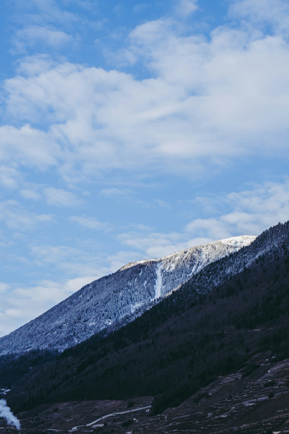 a snowy mountain with a few clouds in the sky