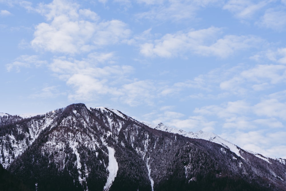 Ein schneebedeckter Berg unter einem bewölkt blauen Himmel