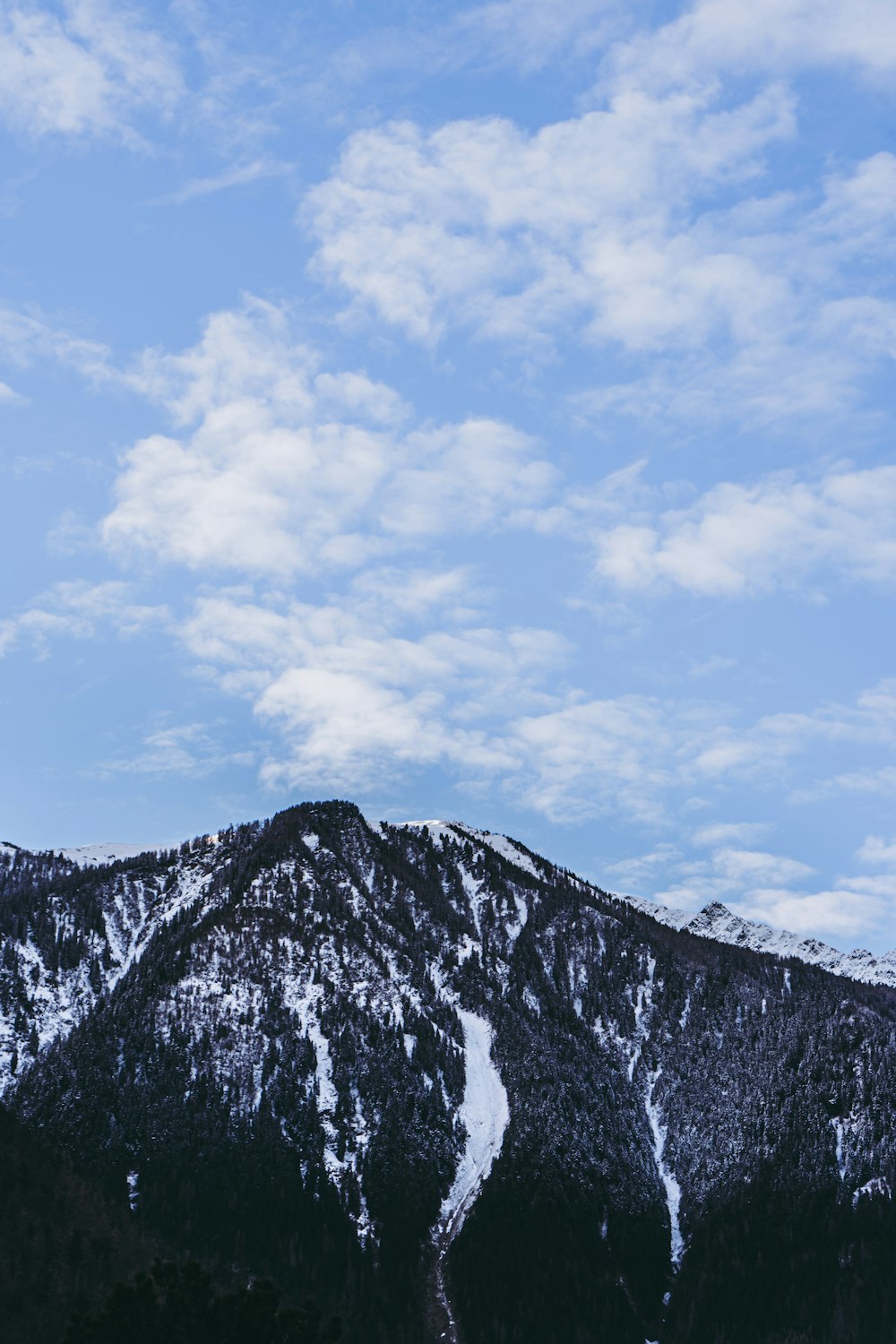 a snow covered mountain under a cloudy blue sky