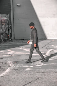Wide city street view with a model in minimalist terravibe attire striding purposefully, shadows stretching on the pavement.