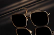 Elegant clubmaster sunglasses resting on a black surface with subtle golden laser-engraved logos