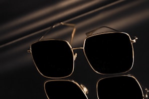 Elegant pair of sunglasses with gold accents reflecting sunlight on a city street