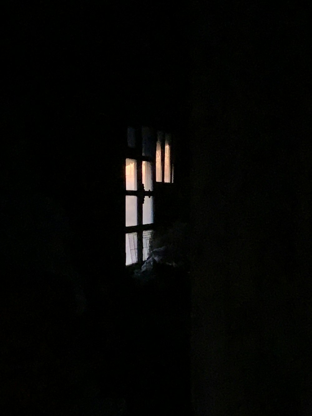 a window in a dark room with a light shining through it