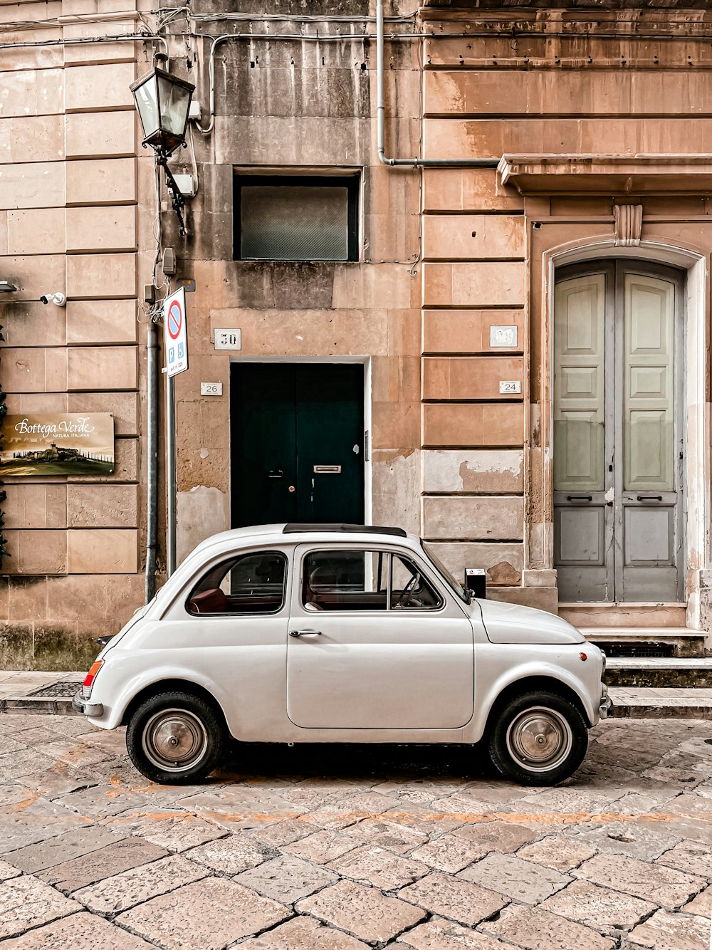 a small white car parked in front of a building