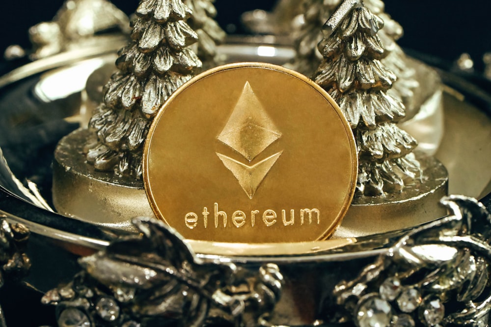 a gold ethereum coin sitting on top of a metal tray