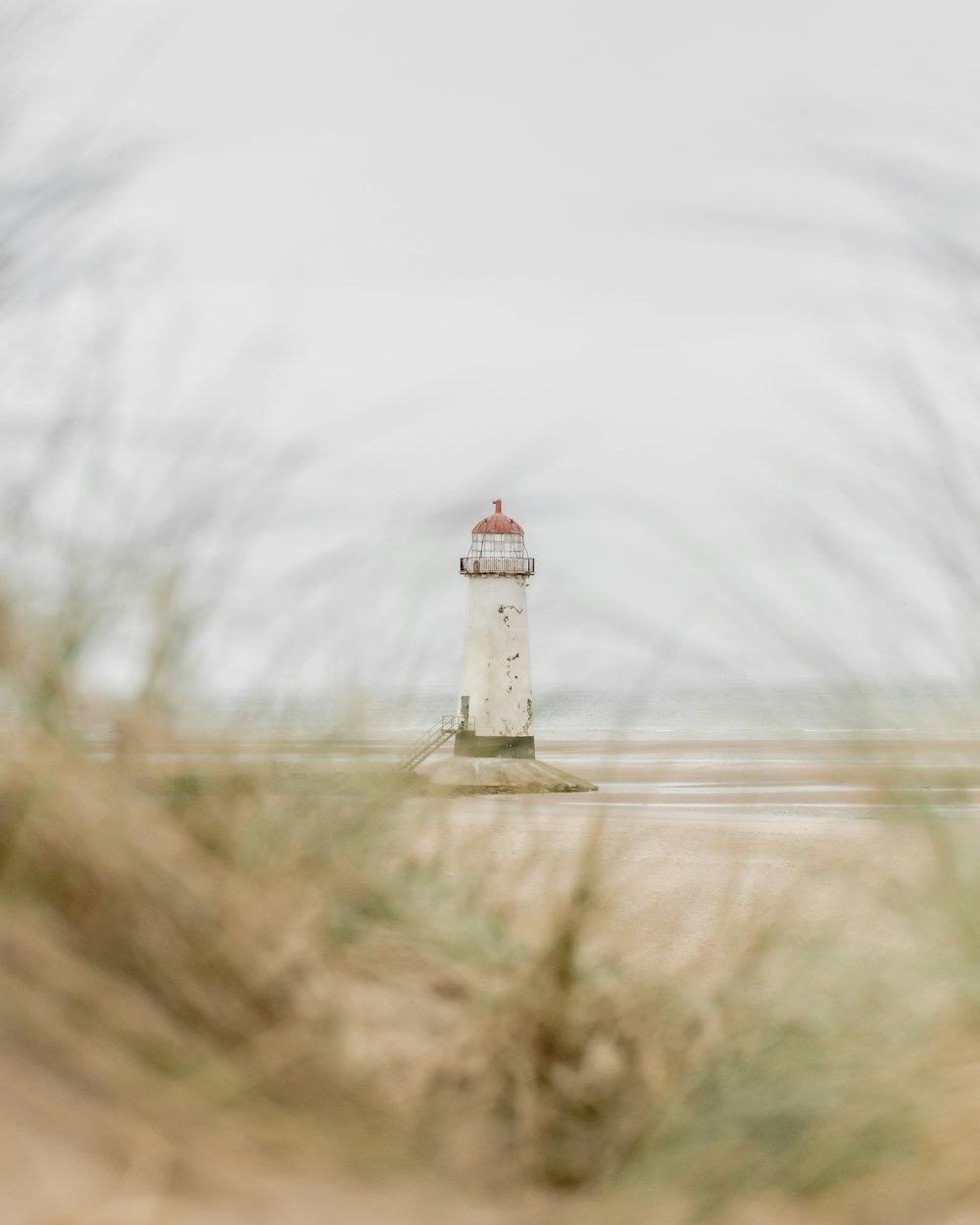 a white and red lighthouse sitting on top of a sandy beach