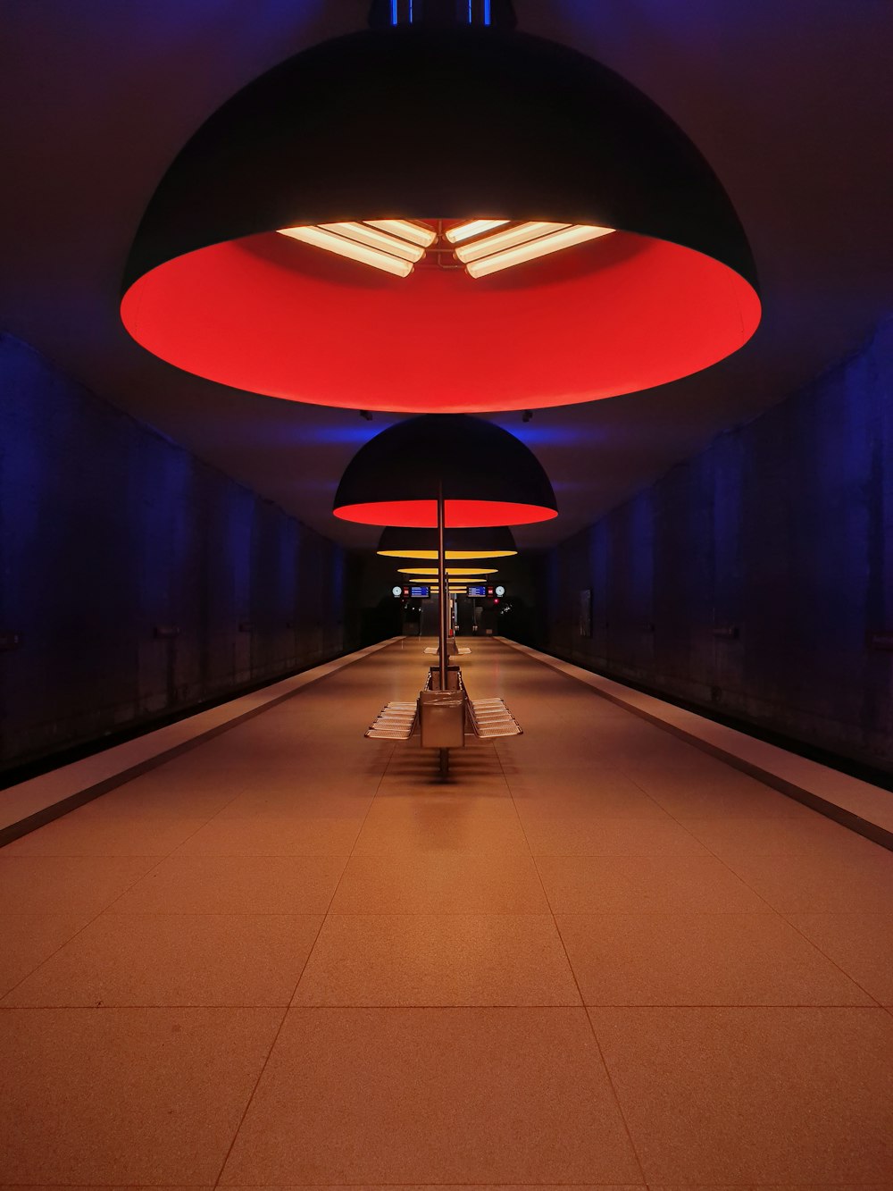 a long hallway with a bench under a red light
