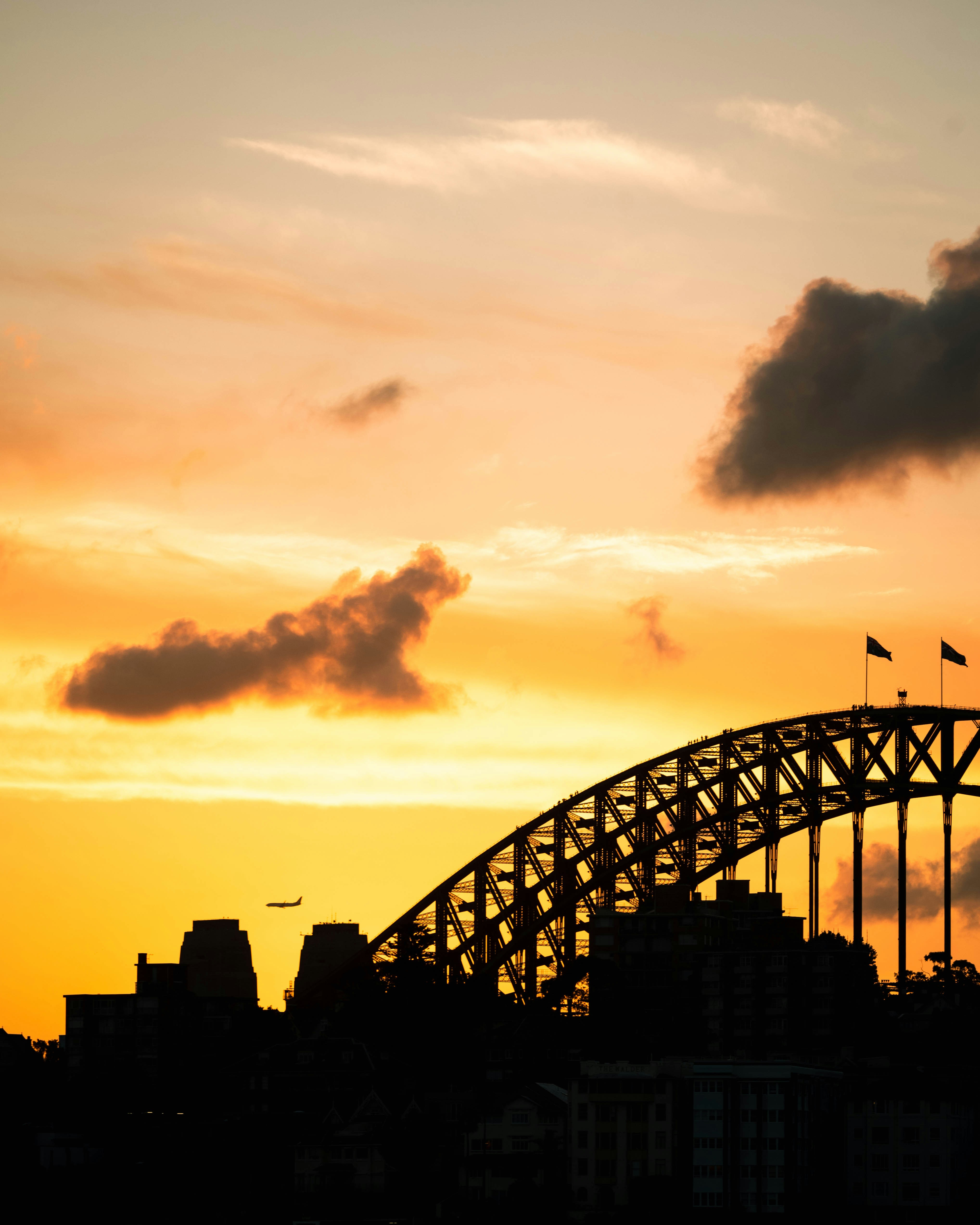 a plane is flying over a bridge at sunset