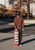 a young man holding a skateboard on a sidewalk