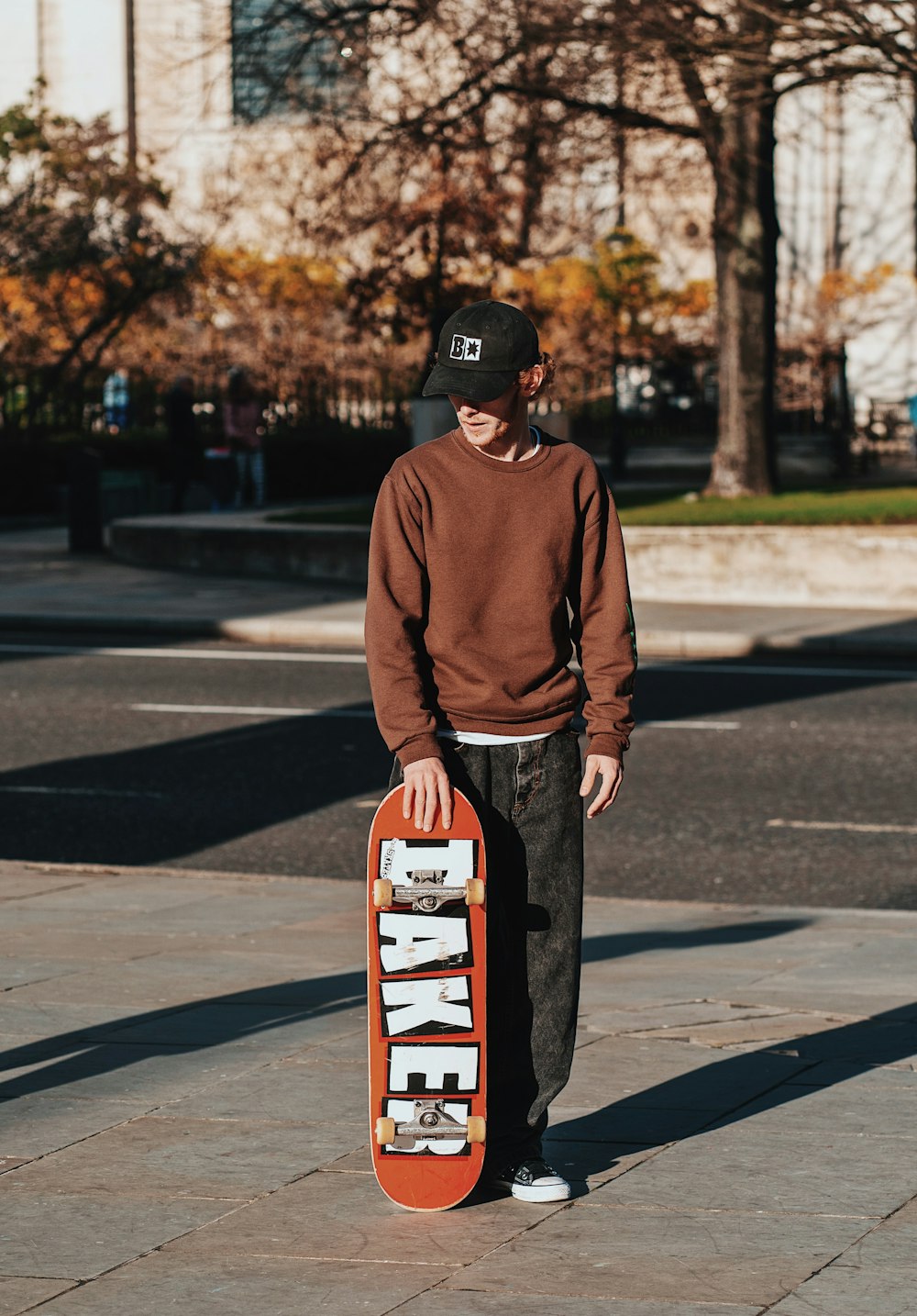 a young man holding a skateboard on a sidewalk