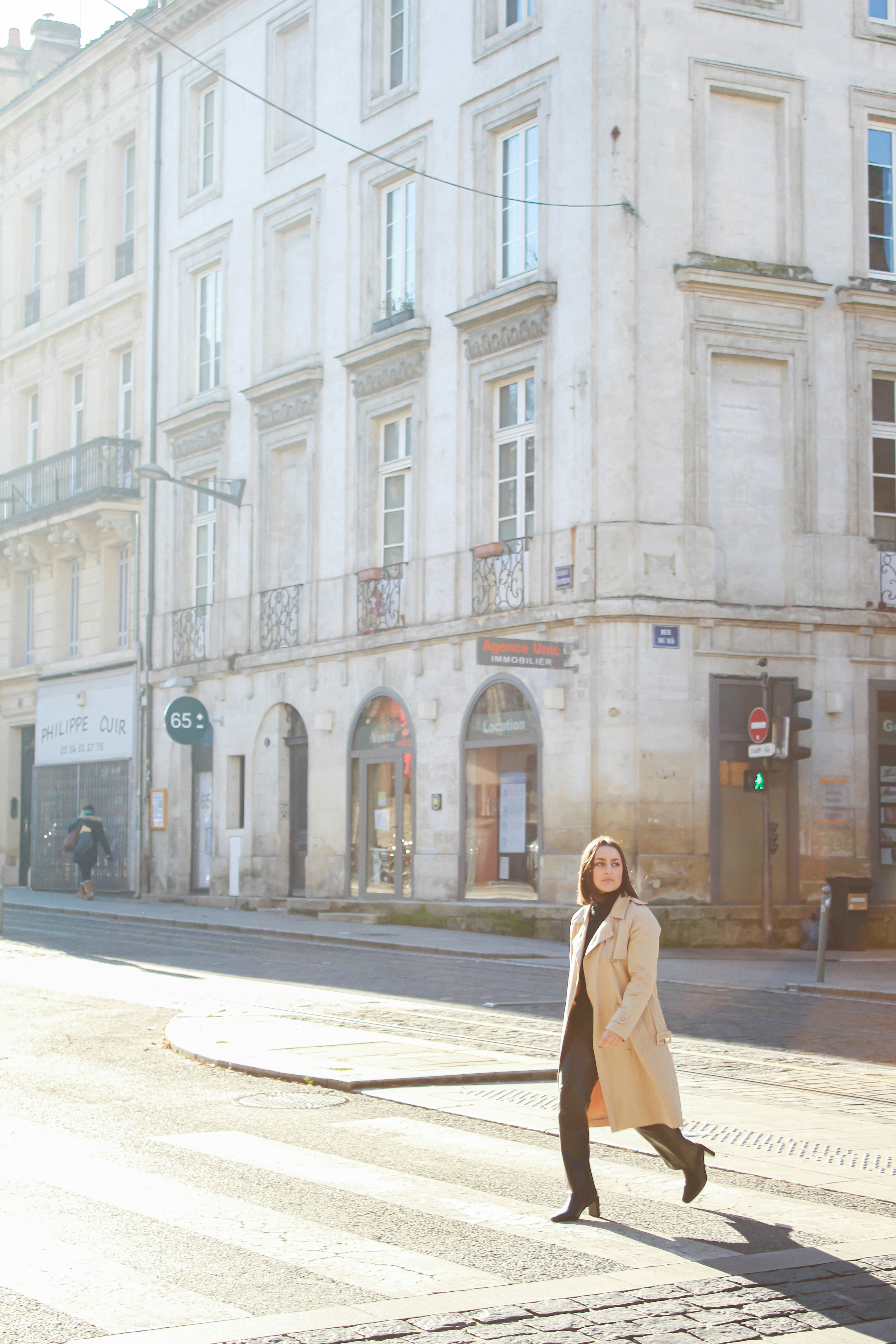 Eine Frau, die über eine Straße neben einem hohen Gebäude geht