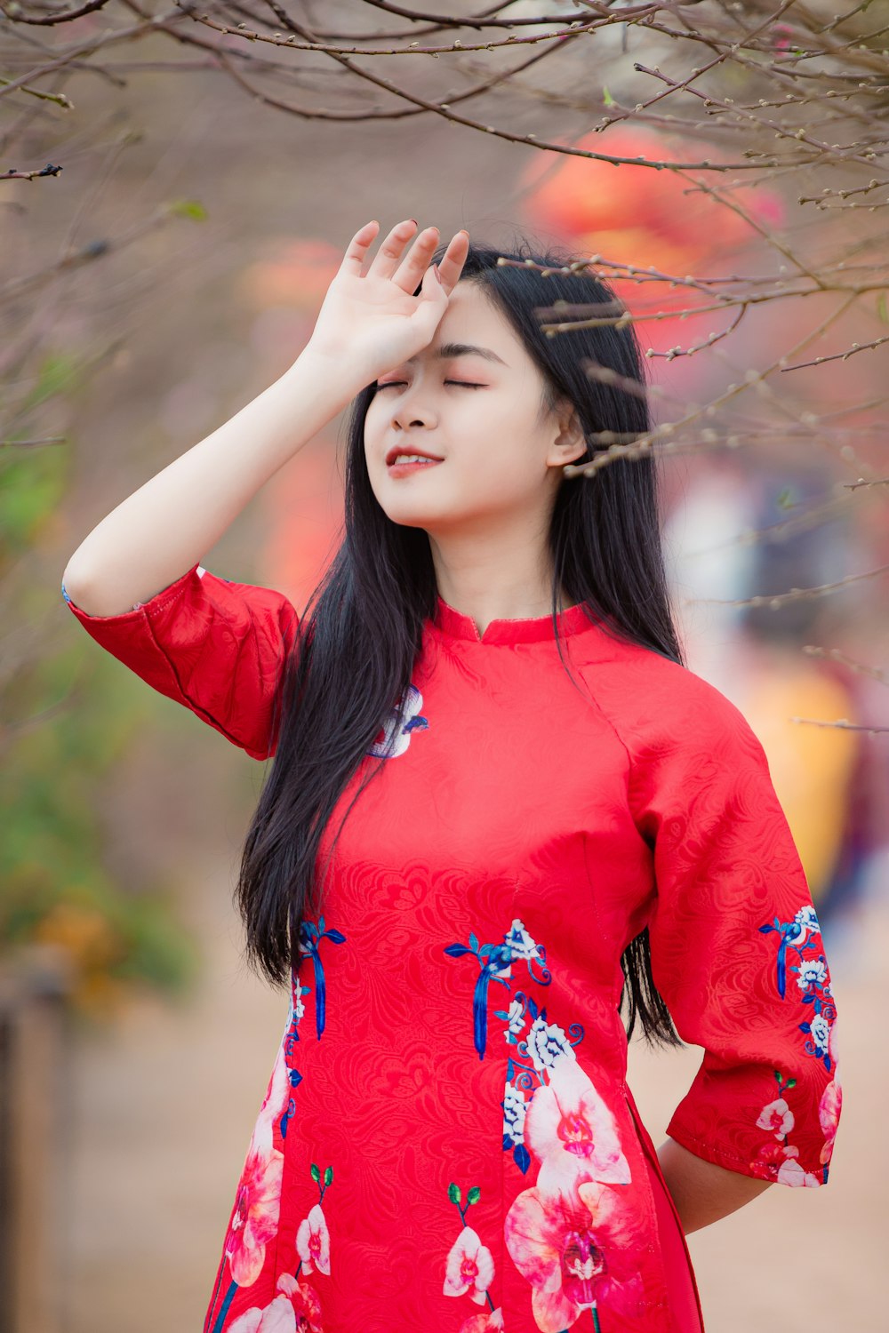 a woman in a red dress standing under a tree