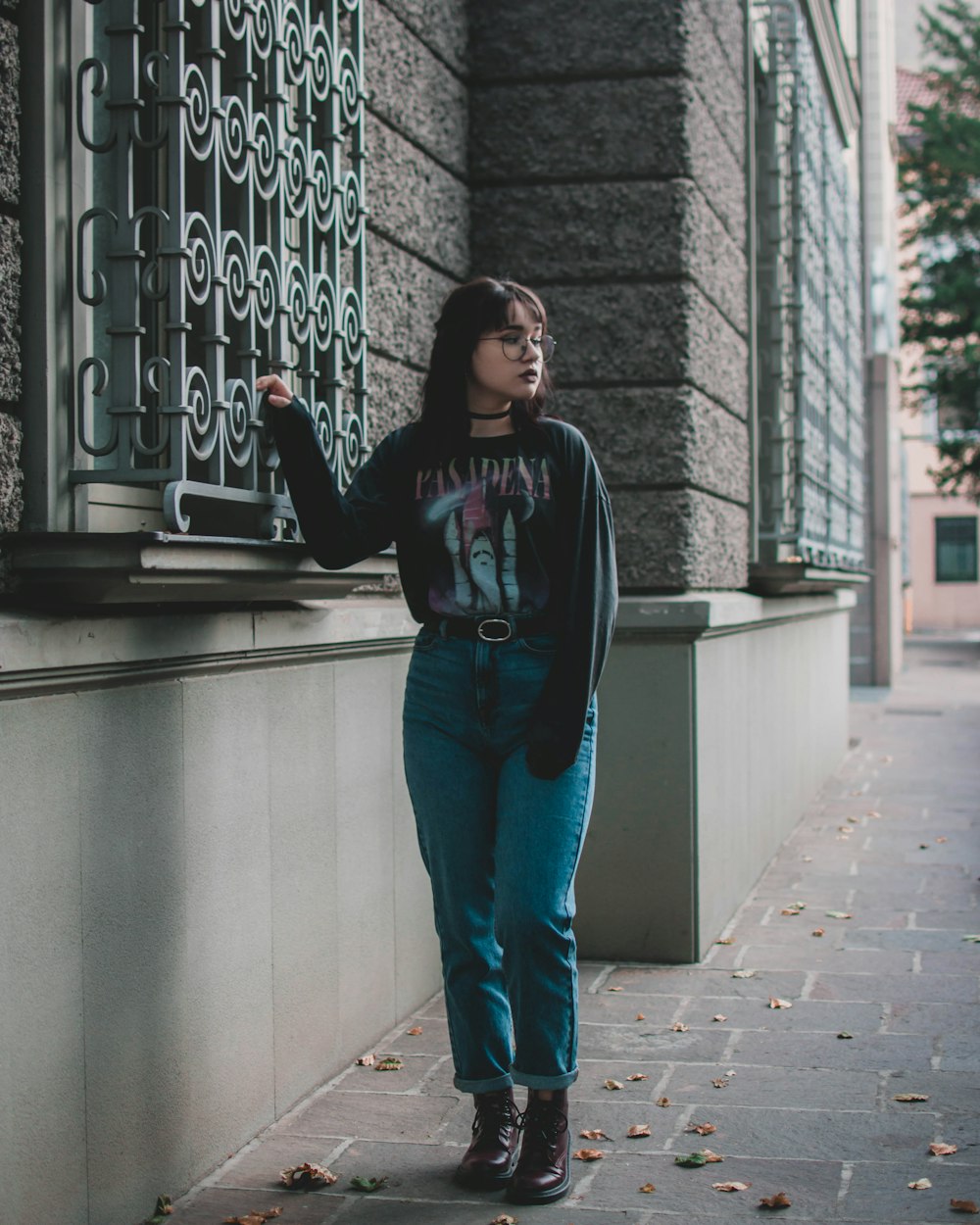 a woman standing next to a window on a sidewalk