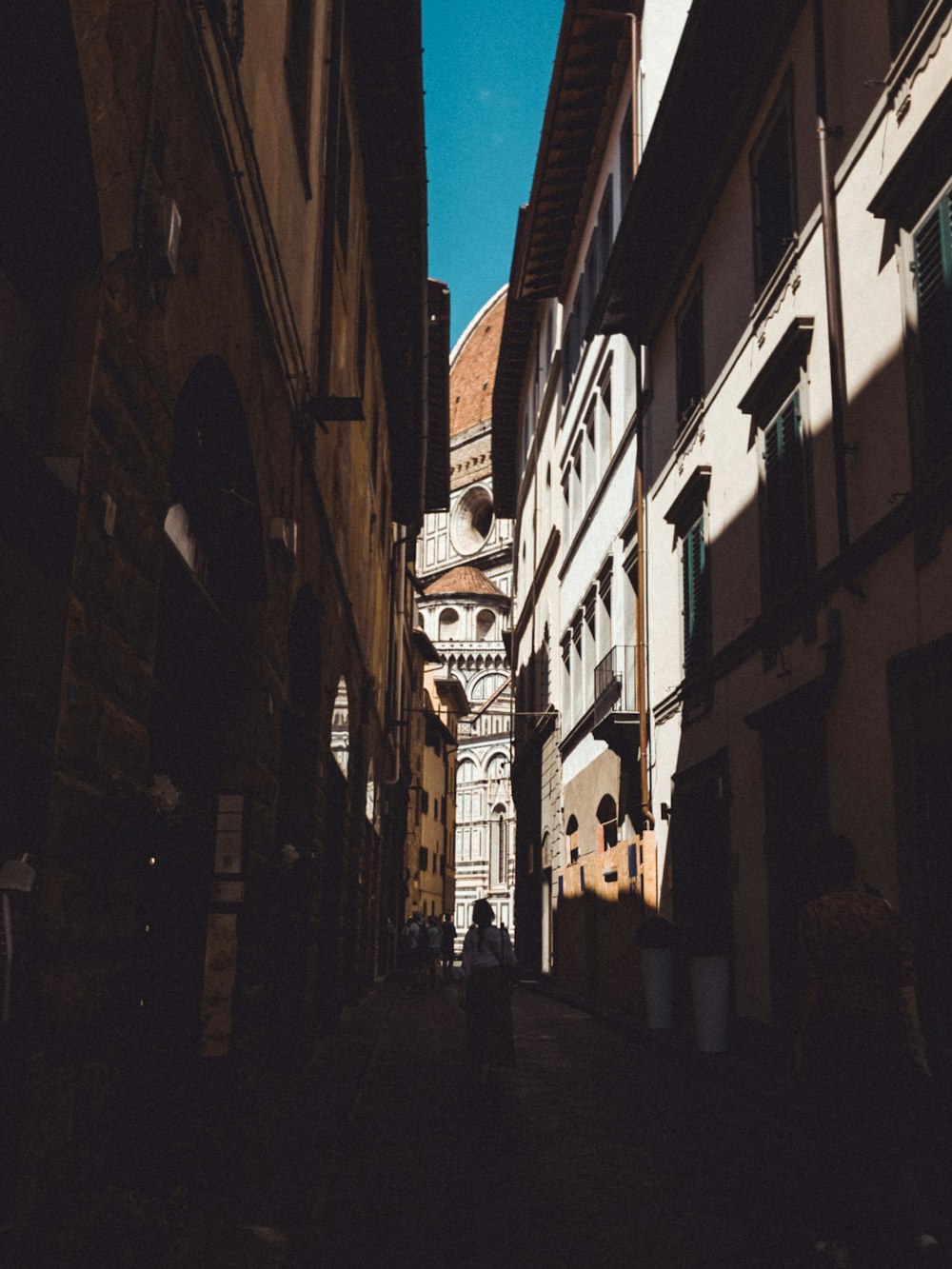 a narrow alley way with a clock tower in the background