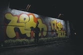 a man standing in front of a wall covered in graffiti