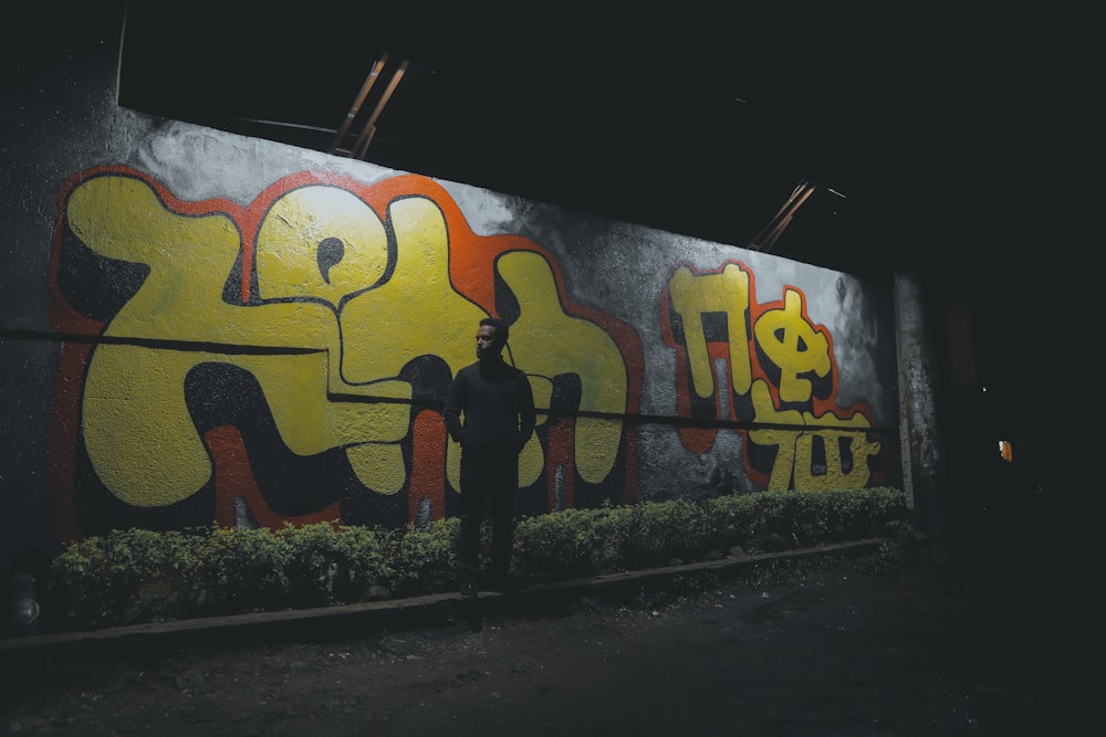 a man standing in front of a wall covered in graffiti