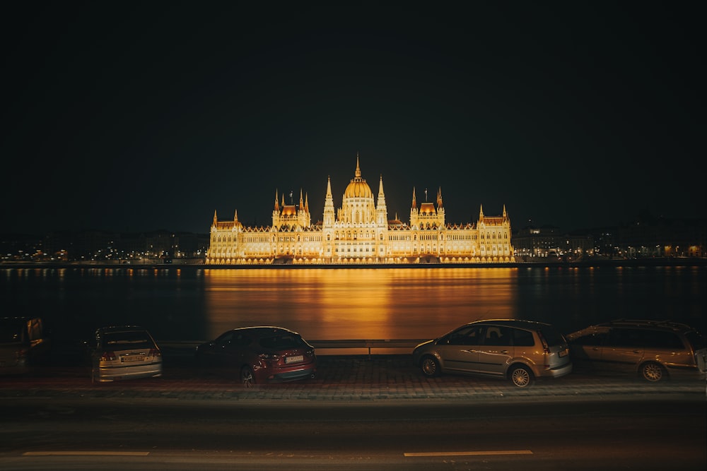 cars parked in front of a large building at night