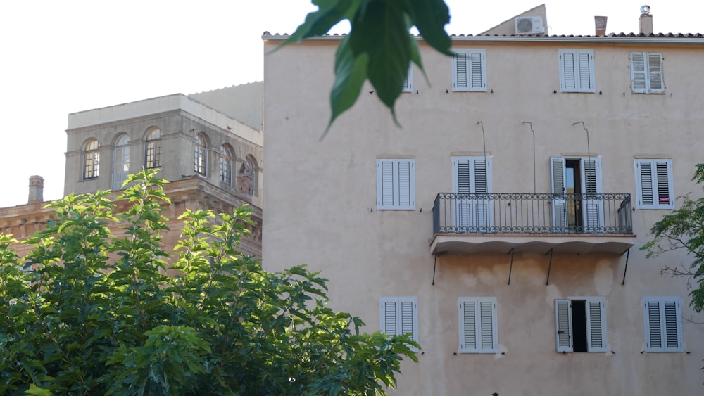 a tall building with white shutters and a balcony