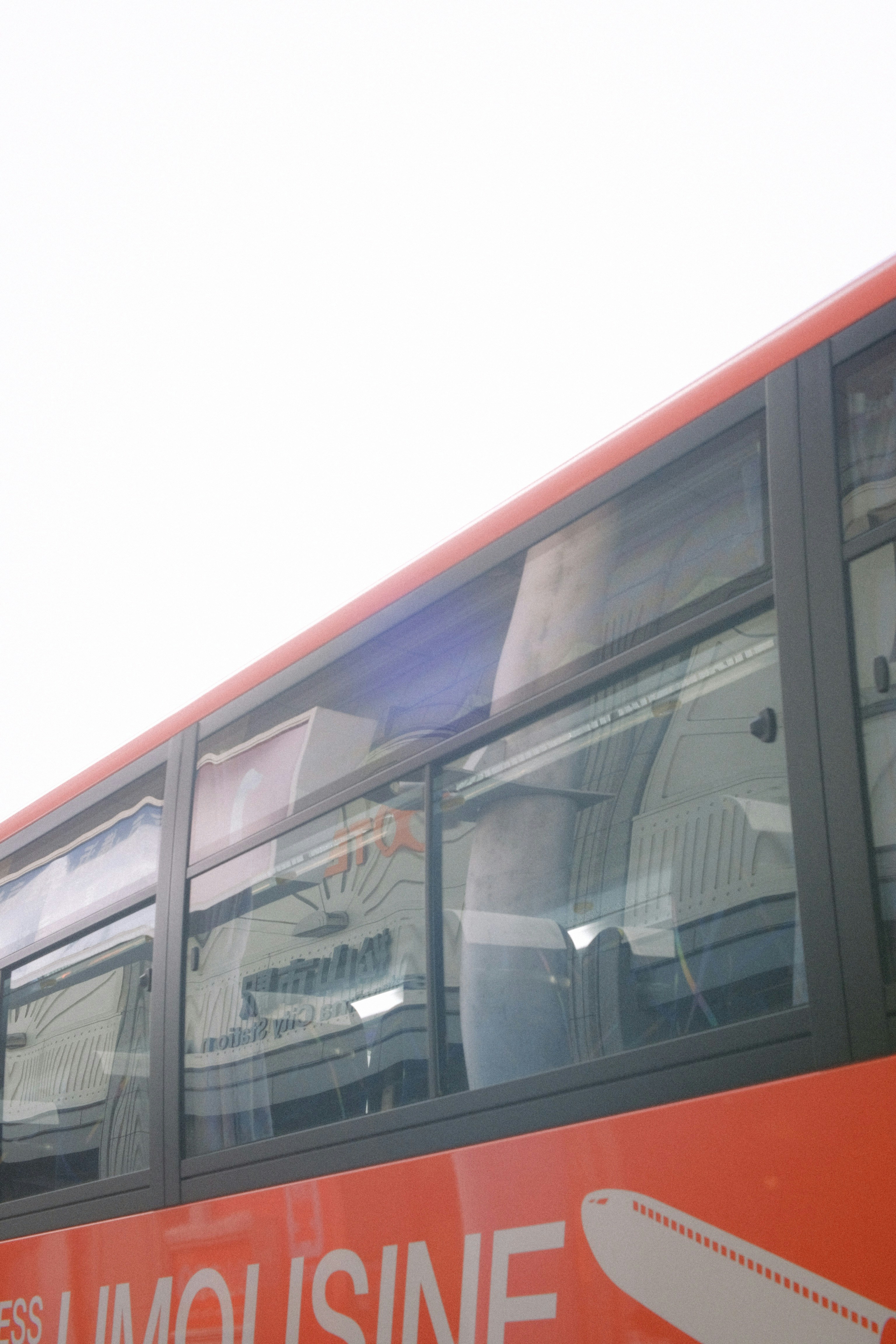 A red double decker bus with a reflection of a person in the window ...